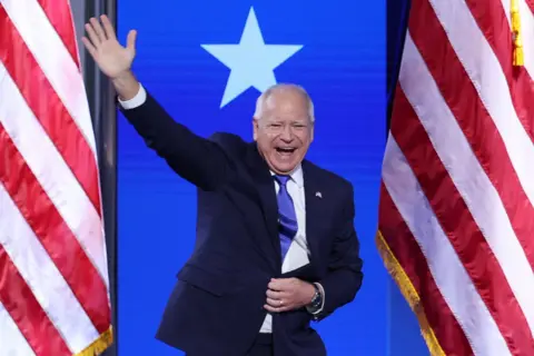 Reuters Tim Walz waves to the crowd as he enters the stage 