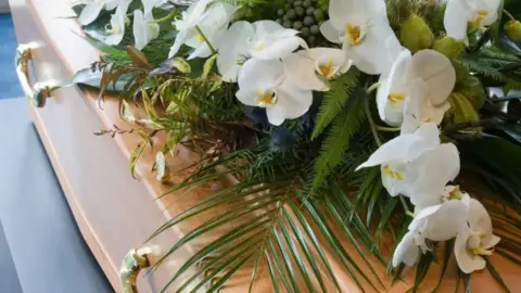 Getty Images White flowers on a wooden coffin