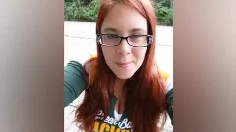 Social media Aimee Betro wearing a Green Bay Packers t-shirt. She has red hair and black-framed glasses