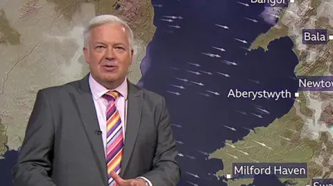 Derek Brockway in front of a weather map