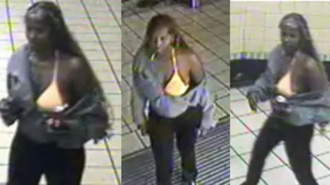 A blurred CCTV image of a woman in a London underground station who is wearing dark trousers, a bright yellow bikini top and a grey hoodie. 