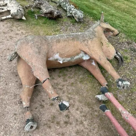 Railtons A concrete cow lying on its side with cracks in its legs