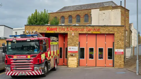 Kent Fire and Rescue Service building with orange doors, red fire engine in front