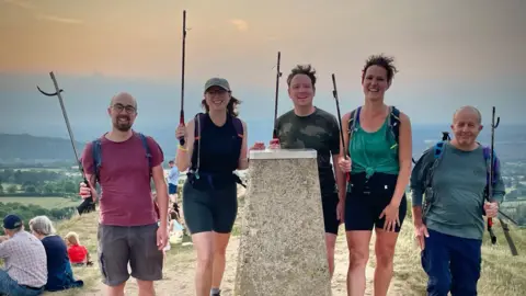 Stroud District Green Party Image of two women and three men standing behind the Painswick Beacon monument with their litter pickers held aloft.