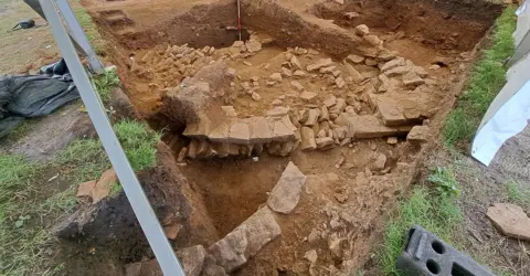 Petuaria ReVisited Project/P Halkon An excavation trench with the stone remnants of the walls of Roman fortifications, which have been uncovered in the light brown earth