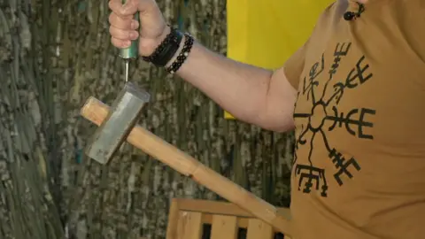 Kevin McGregor / BBC The extractors work by using powerful magnets. The inventor of the magnetic extractor Oleh Bykov demonstrates their power by holding up a sledgehammer.