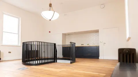 North Yorkshire Council A modern looking room with a staircase arriving from below into the middle of the floor.