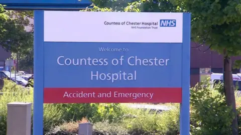 BBC A blue sign, with Countess of Chester Hospital written on in white writing above a red strap-line, which reads Accident and Emergency.
