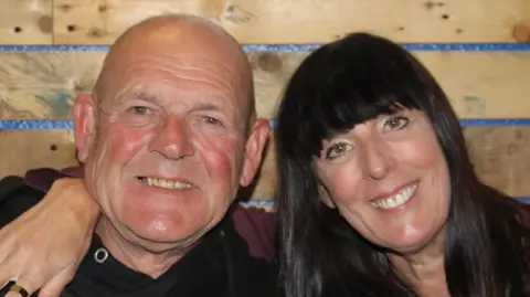 Family handout Tom and Julia smile as they pose together for a picture. Julia has her arm around his shoulder.