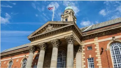 BBC A grand brown building with arched windows. Four pillars are at the front.