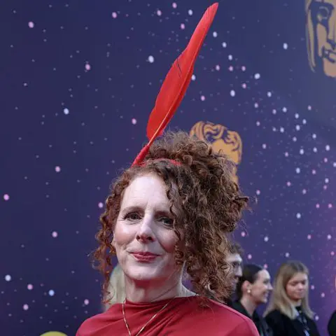 Getty Images Maggie O'Farrell in a red dress with a red quill headpiece