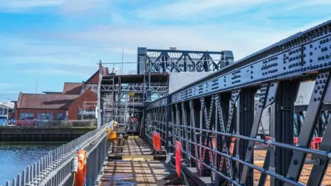 North East Lincolnshire Council A bridge with a low railing on the left and a high railing on the right. There is scaffolding at the far end.