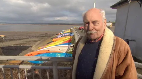 Cllr Ken Hind of Bideford Town Council standing in front of tied up water craft in the River Torridge.
