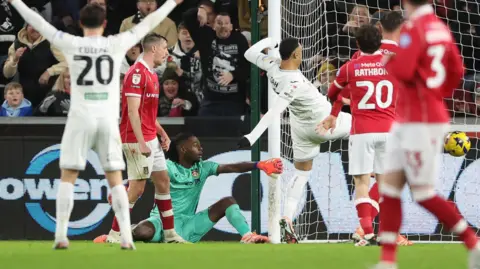 Arthur Okonkwo (in green) drops the ball and allows Adam Idah to score for Swansea