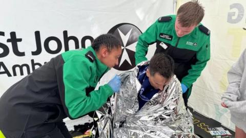 Becky James and Matthew Cleave assist Mr Walker in the St John Ambulance tent 