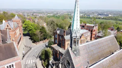A building with large green spire can be seen in the foreground, with views across large parts of residential north west London in the background