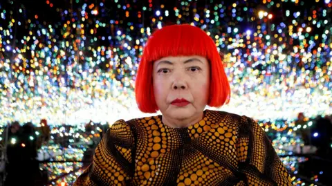 Japanese artist Yayoi Kusama poses for a photograph inside her Infinity Mirrored Room installation titled "The Souls of Millions of Light Years Away" during a media preview of her new exhibition at the David Zwirner gallery in New York, U.S.