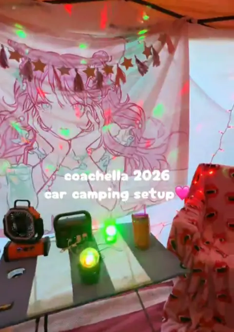 Ali Calder Picture of an interor of a tent with a pink theme and an electric fan, disco lights and tapestries hung from tent walls.