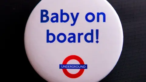 A white button badge with the words "Baby on board!" in blue, written above the London Underground logo.