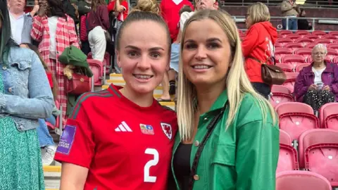 Tara Male Lily Woodham stands in a Wales football shirt with her friend at a game