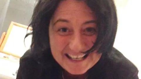 A woman with short dark hair smiles at the camera