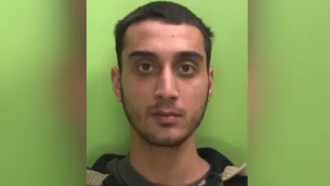Nottinghamshire Police A mugshot of Junaid Farrukh against a green background. 