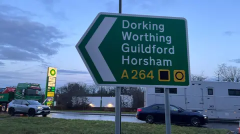 A road sign. It shows the towns of Dorking, Worthing, Guildford and Horsham. 
