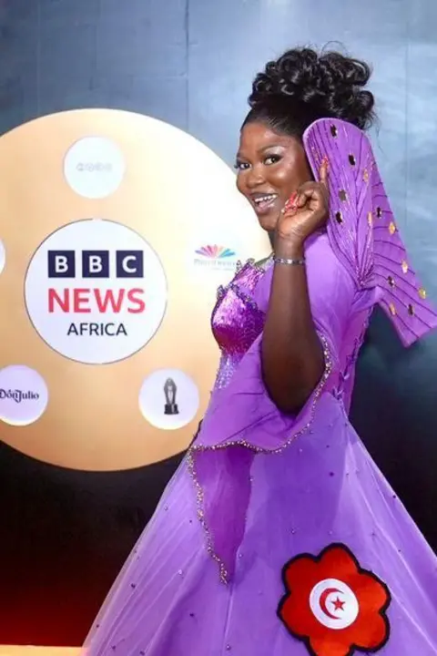 BBC/MOBOLAJI OLATUNDE  Nollywood actor and producer Monica Friday, showed off the flags of seven countries, including that of Iran, embroidered on her purple ball gown