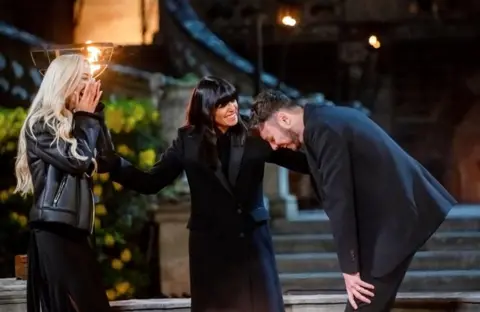 BBC / Studio Lambert Three people - Leanne, Claudia and Jake - stand together outside, smiling and laughing. They are all wearing black and look in shock