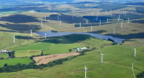 Robert Wright Aerial image of a reservoir surrounded by grass covered hills with wind turbines scattered around the area far into the distance