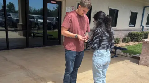 Courtesy of Annie Ramos and family A young man and young woman hold out their hands with a ring outside a building during the daytime.