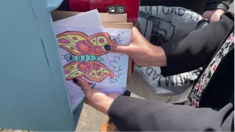 A woman removed a sheaf of letters, cards and drawings from a blue postbox