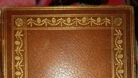 Ateeq Ahmad The exterior of a leather-bound notebook. The cover is dark and features a golden design around the border.
