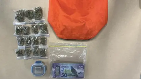 New Zealand Police Small plastic bags containing cannabis, part of an orange bag, and banknotes in another plastic bag