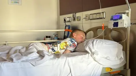 Family photo Michael, a young boy with fair hair, asleep in his hospital bed