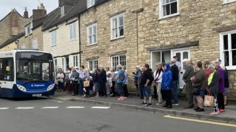 People queuing for a bus in Wotton-under-Edge