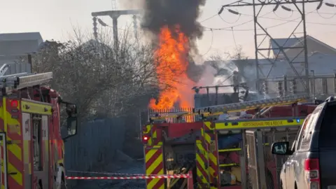 Two fire engines can be seen in front of a fire at a substation