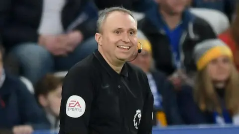Getty Images Darren Cann wearing black assistant referee uniform. He is smiling. 