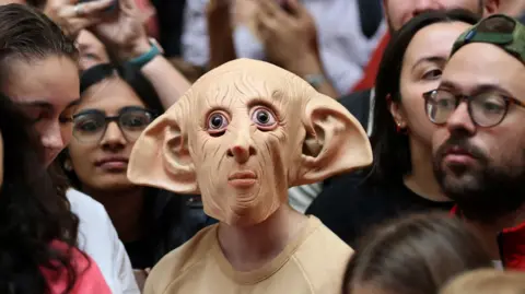 A fan wearing a Dobby the elf mask among a crowd of Harry Potter fans in London King's Cross station last year. 