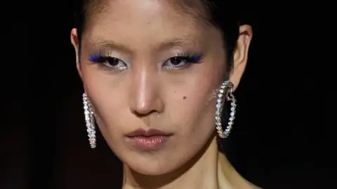 Getty Images Model astatine  New York manner  week connected  the runway wearing bluish  mascara and metallic  earrings 