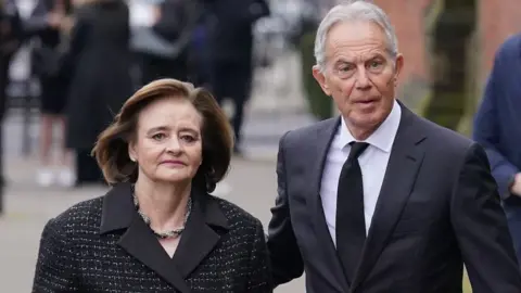 PA Media Former prime minister Tony Blair and his wife Cherie Blair attend the funeral service of Derek Draper