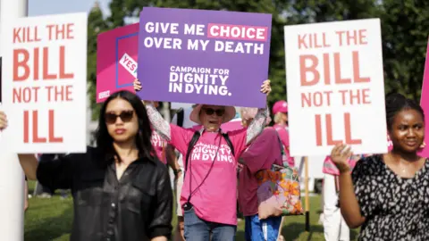 EPA Campaigners outside Parliament hold up placards. Two women are holding a placard reading: "Kill the bill not the ill". Another woman has a poster which say: "Give me choice over my death."