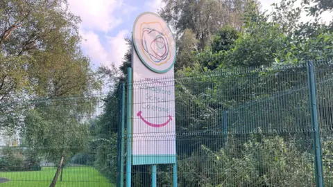 BBC a sign seen through a wire gate reads "Welcome to Sandelford School Coleraine"