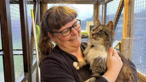 Lady holding up a grey and white stripped cat