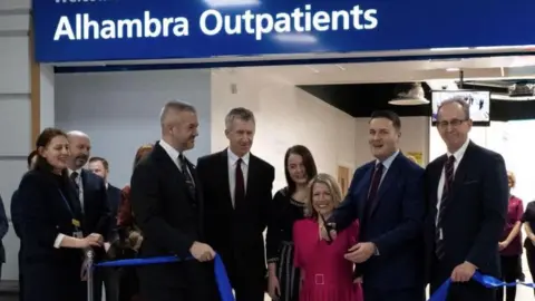 An image of a ribbon cutting service at the entrance to the outpatients service. Health Secretary Wes Streeting is pictured with scissors in his hand alongside Barnsley council leader Sir Steve Houghton, local MPs Marie Tidball, Dan Jarvis and Stephanie Peacock and South Yorkshire Mayor Oliver Coppard.