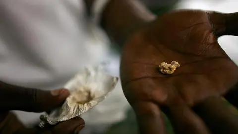 An individual holds a nugget of gold in his palm