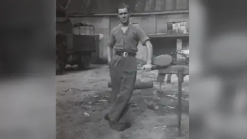 Roy S Crowshaw A black and white photo of Monty, taken in an unidentified location while serving in Europe. He is a young man in the photograph with short brown hair. He is in his shirt sleeves and in high waisted military trousers.