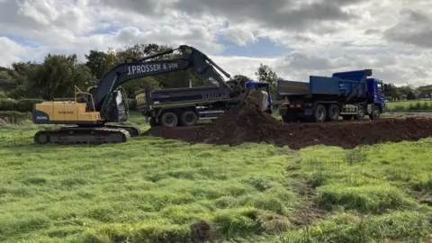 Environment Agency digger bringing materials