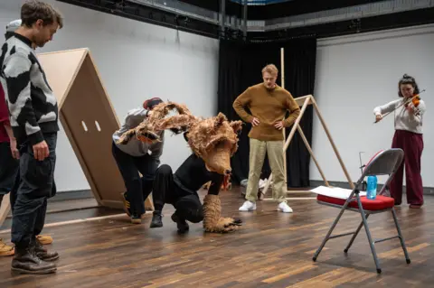 Albany Theatre Actors rehearse for a production of The Bear Who Went to War. They can be seen playing a violin with two actors dressed as Wojetek the bear