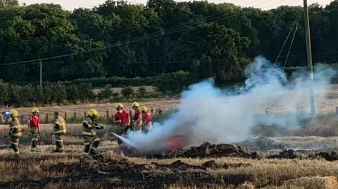 Shropshire Fire and Rescue Service A number of firefighters attempting to extinguish a burning field
